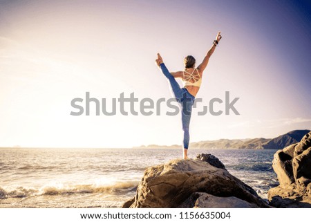 Woman training yoga on the beach at sunset