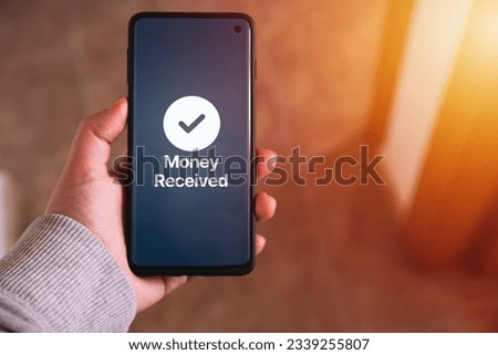 Woman transfering money online using apps on smartphone. Selective focus. Concept of financial transactions with mobile devices. Smartphone screen displaying money transfer confirmation.