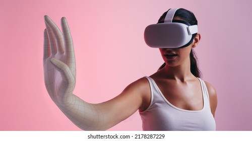 Woman transforming into a 3D avatar in the metaverse. Female gamer entering a game while wearing virtual reality goggles. Young woman experiencing immersive technology in a studio. - Shutterstock ID 2178287229