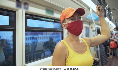 Woman travel caucasian ride at overground train airtrain with wearing protective medical red mask. Girl tourist at airtrain with respirator. Pandemic virus Coronavirus covid-19. People in mask.