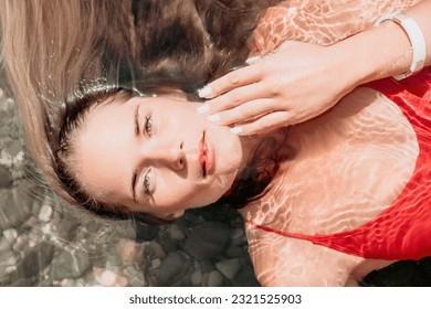 Woman travel portrait. close-up portrait of a happy woman with long hair in a red bikini, floating in water and smiling at the camera. - Powered by Shutterstock