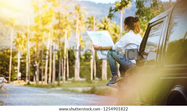 woman travel relaxing nature mountain map\
navigation. Sit on the car and browse the\
map.