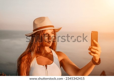 Woman travel sea. Happy tourist in hat enjoy taking picture outdoors for memories. Woman traveler posing on the beach at sea surrounded by volcanic mountains, sharing travel adventure journey.
