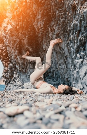 Woman travel sea. Sporty happy middle aged posing on a beach near the sea on background of volcanic rocks, like in Iceland, sharing travel adventure journey