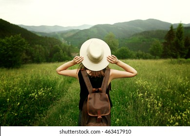woman traveler with backpack holding hat and looking at amazing mountains and forest, wanderlust travel concept, space for text, atmospheric epic moment - Shutterstock ID 463417910