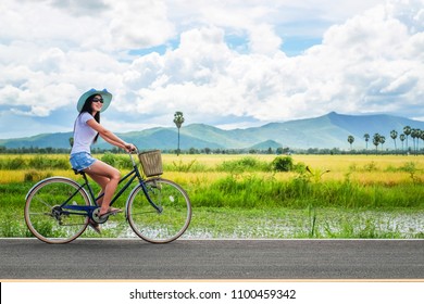 woman traveler enjoying for  view of rice field. Asian lady tourist riding a bicycle and looking for view of nature on holiday. - Powered by Shutterstock