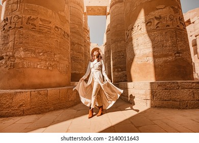 Woman traveler explores the ruins of the ancient Karnak temple in the city of Luxor in Egypt. Great row of columns with carved hieroglyph - Shutterstock ID 2140011643