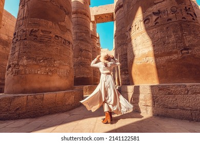 Woman traveler explores the ruins of the ancient Karnak temple in the city of Luxor in Egypt. Great row of columns with carved hieroglyph - Shutterstock ID 2141122581