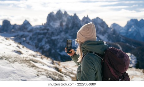 Woman traveler making photo with her smartphone in Tre Cime di Lavaredo in snow South Tyrol, Italy. Winter landscape of Dolomites, Italy - Shutterstock ID 2229056889