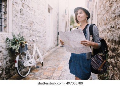 Woman traveler with map in old town near vintage bicycle - Shutterstock ID 497053780