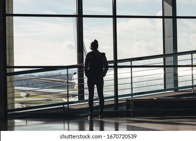 Woman Traveler On Empty Airport Looking Through Window Worried About Coronavirus.