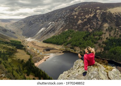 A woman traveler in a red jacket in the Spink Viewing Spot in Wicklow mountains national park, Ireland
