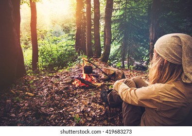 Woman Traveler Relaxing In Forest And Cooking Food In Kettle On Fire Travel Lifestyle Concept Vacations Outdoor Picnic Bivouac In Forest