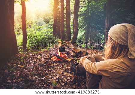 Woman traveler relaxing in forest and cooking food in kettle on fire Travel Lifestyle concept vacations outdoor picnic bivouac in forest