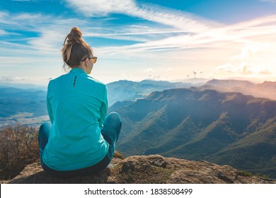 Woman traveler sitting in the edge of a cliff looking the mountains. Adventure solo traveling lifestyle. Wanderlust adventure concept. Active weekend vacations wild nature outdoor. Autumn fall forest. - Powered by Shutterstock