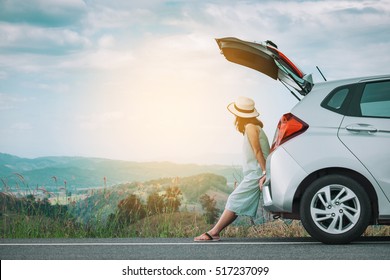 Woman traveler sitting on hatchback car with mountain background in vintage tone