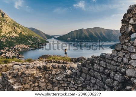 Woman traveler Standing on ruins of ancient Illyrian fort Rizon. Female enjoying views of Kotor Bay among the oldest settlement in Boka Kotorska above town of Risan. Travel Montenegro concept.