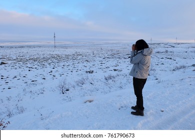 Woman traveler took a photo with beautiful landscape of tundra cover with snow on the way to Teriberka, Russia