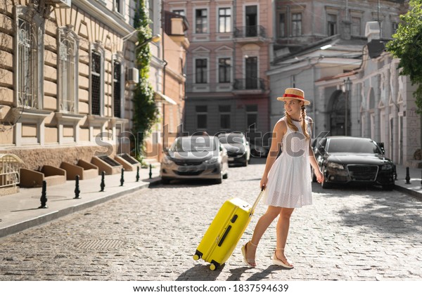 Woman traveler tourist walks with luggage around
the city.