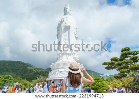 Woman traveler visiting at Linh Ung Pagoda temple or Lady big Buddha. Tourist with blue dress and hat traveling in Da Nang city. Vietnam and Southeast Asia travel concept