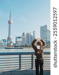 woman traveler visiting in Shanghai, China. Female Tourist with backpack sightseeing Shanghai view of Lujiazui in The Bund of Shanghai. landmark and popular for tourism attractions. Vacation concept