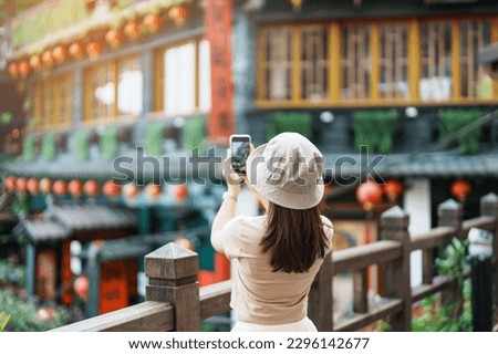 woman traveler visiting in Taiwan, Tourist taking photo and sightseeing in Jiufen Old Street village with Tea House background. landmark and popular attractions near Taipei city. Travel concept