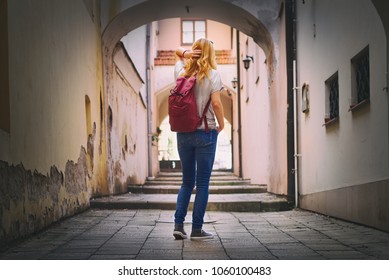 Woman traveler walking through arcade in european historic city. Hipster girl traveling in Europe. Tourism concept
