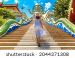 Woman traveler wearing blue dress and straw hat at Big Buddha on Koh Samui, Thailand in a summer day