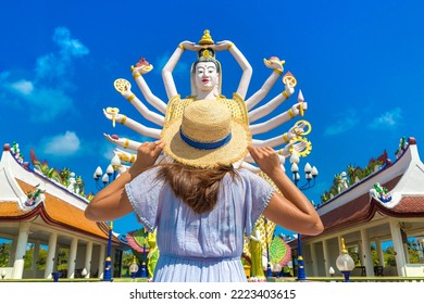 Woman Traveler Wearing Blue Dress And Straw Hat At  Statue Of Shiva In Wat Plai Laem Temple, Samui, Thailand In A Summer Day