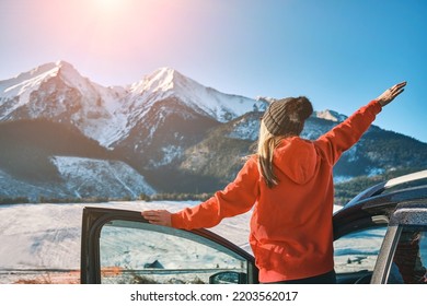 Woman traveling exploring, enjoying the view of the mountains, landscape, lifestyle concept winter vacation outdoors.Female standing near the car in sunny day, travel in the mountains, freedom.