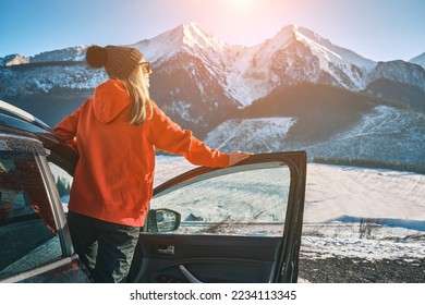 Woman traveling exploring, enjoying the view of the mountains, landscape, lifestyle concept winter vacation outdoors. Female standing near the car in sunny day, travel in the mountains. - Shutterstock ID 2234113345