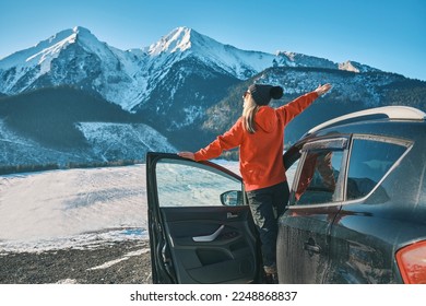 Woman traveling exploring, enjoying the view of the mountains, landscape, lifestyle concept winter vacation outdoors. Female standing near the car in sunny day, travel in the mountains, freedom. - Powered by Shutterstock