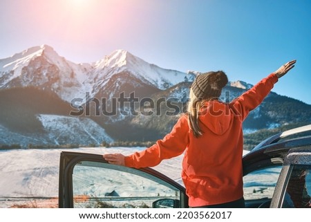 Woman traveling exploring, enjoying the view of the mountains, landscape, lifestyle concept winter vacation outdoors.Female standing near the car in sunny day, travel in the mountains, freedom.