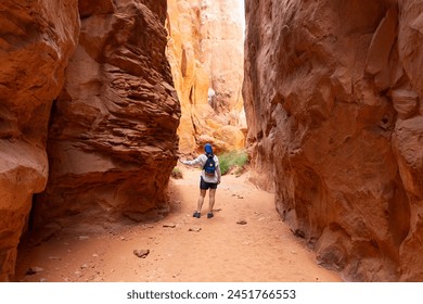 Woman Traveling through Narrow Sandstone Desert Rock Canyon Hiking Trail in Fiery Furnace, Arches National Park, Utah, United States - Powered by Shutterstock