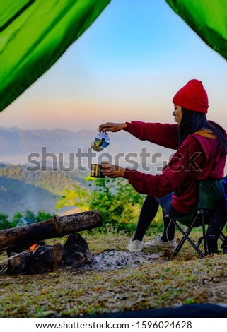 woman traveller with hot drink in front of living tent, prepare hot drink in the morning, wild and adventure trip of alone woman