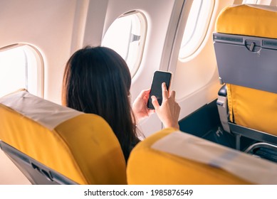 Woman Traveller Passenger Sitting At Airplane Seat Using Smartphone Onboard.