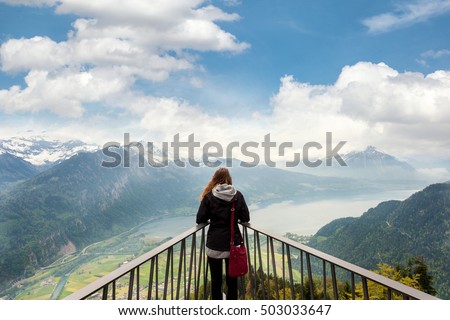 Woman traverler looking aerial view of the city district and Interlaken from viewpoint at Harder Kulm in Interlaken, Bern, Switzerland.