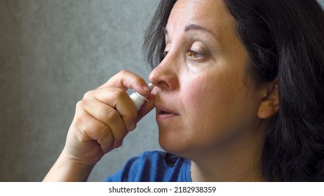 A woman treats a runny nose. Using a medicated spray Allergy. The cure for the disease. Cold symptoms. Infectious virus. Covid. Coronovirus. Indoors. Close-up. - Shutterstock ID 2182938359