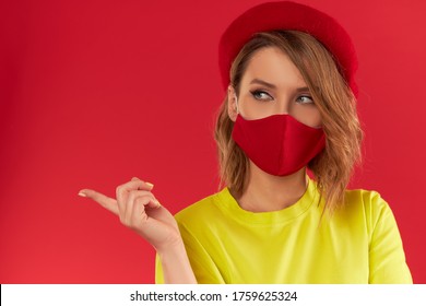 Woman In Trendy Fashion Outfit During Quarantine Of Coronavirus Outbreak. Model Dressed Protective Stylish Handmade Face Mask On Red Studio Background