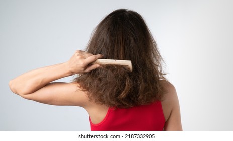 A woman tries to comb her tangled hair from behind with a comb - hair problems. High quality photo - Shutterstock ID 2187332905