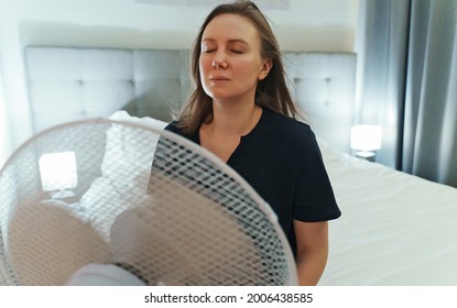 Woman Tries To Cool Off During The Intense Heat In Front Of Cooling Fan.