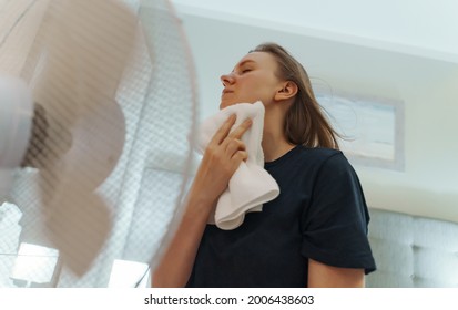 Woman Tries To Cool Off During The Intense Heat In Front Of Cooling Fan.