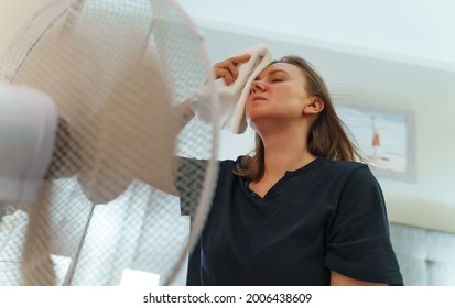 Woman Tries To Cool Off During The Intense Heat In Front Of Cooling Fan.