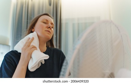 Woman Tries To Cool Off During The Intense Heat In Front Of Cooling Fan.