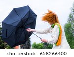 A woman tries to hold her umbrella in a strong wind