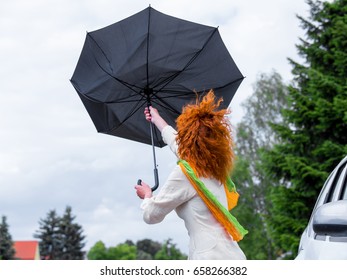 A Woman Tries To Hold Her Umbrella In A Strong Wind