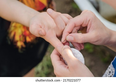 A woman tries to pull a splinter out of a teenager's hand. Shard in a child's hand