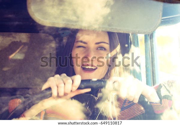 woman truck driver in the car. Girl\
smiling at camera and holding the steering\
wheel