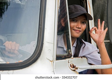 Woman Truck Driver In The Car. Young Asian Woman Driving A Truck. Truck Driver Shows From Open Window The Perfect Gesture. Successful Gesture O.K. From Driver Of Truck. Asian Lorry Driver.