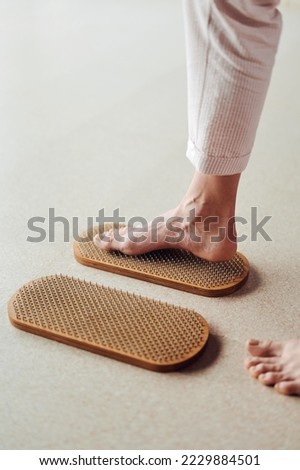 Woman try standing on Wooden Sadhu board with nails, yoga desk for regular practice, relieves nervous stress, tiredness, emotional overexcitation
